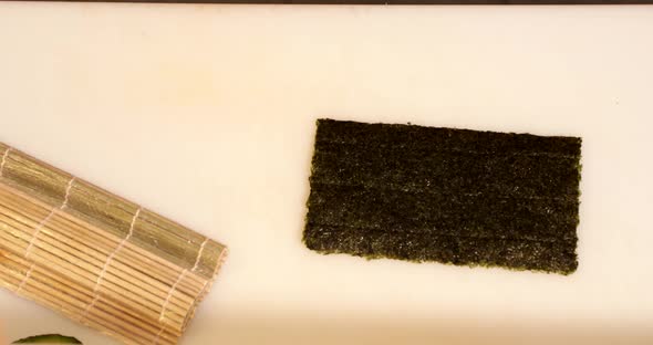 A Piece Of Nori And A Bamboo Mat (Makisu) On The Table - Sushi Making - overhead panning shot, slow