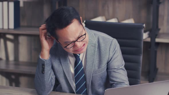 Stressed businessman manager feeling tired while sitting at his working place in the office.