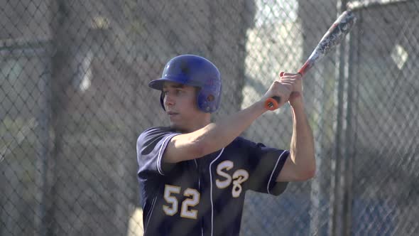A young man practices baseball at the batting cages.
