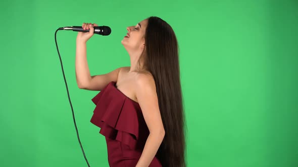 Portrait of Beautiful Young Woman Sings Song Into Microphone