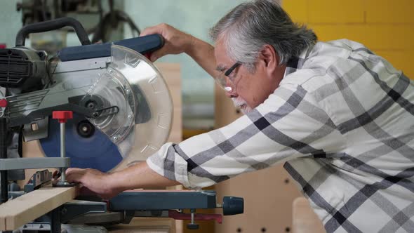 Senior man using electric cutter to cut wood