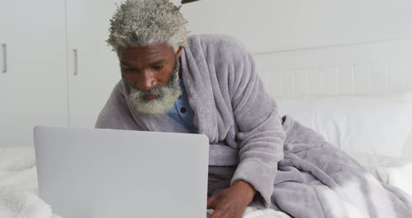 Senior man using laptop in bed at home