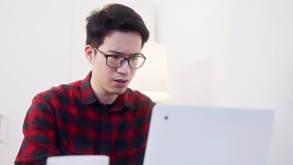 Upset Young Asian Businessman Finding Mistakes in Documents