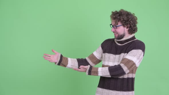 Happy Young Bearded Man Showing Something and Looking Surprised