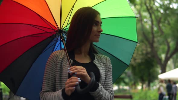 Portrait of a Young Beautiful Happy Woman Walking and Spinning Her Colorful Umbrella in a Rainy Day