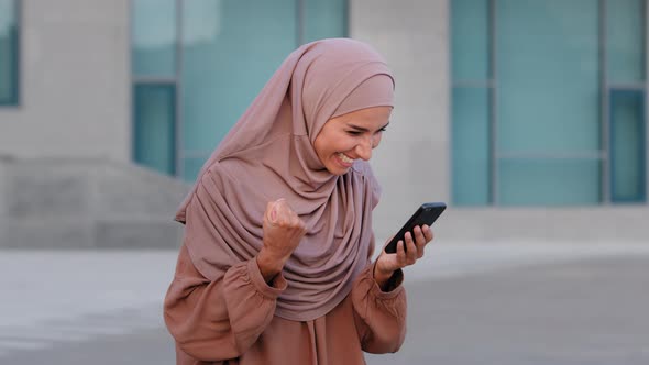 Portrait of Happy Muslim Business Woman Enjoy Success on Mobile Phone Outdoors