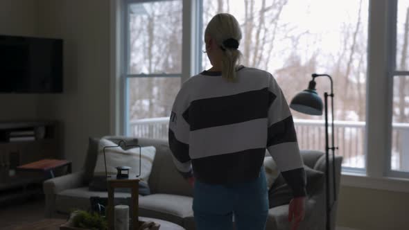 woman walking to the couch to lay down and scroll through tablet while drinking coffee in a nice hou