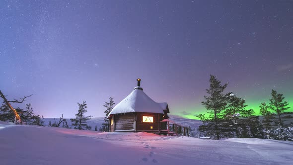 Timelapse of a wilderness cabin in winter night under starry sky and northern lights in Lapland, Fin