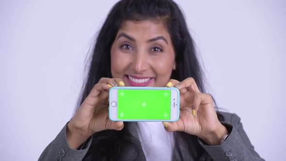 Face of Young Happy Persian Businesswoman Thinking While Showing Phone