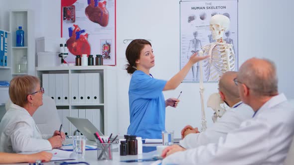 Medical Young Nurse Presenting Spine Anatomy with Human Skeleton Model