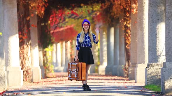 Young girl with suitcase in red ivy alley. Autumn season time