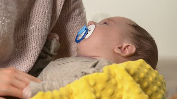 Charming Baby With Dummy Lying on Moms Arms, Lady Patting Belly, Colic Reduce