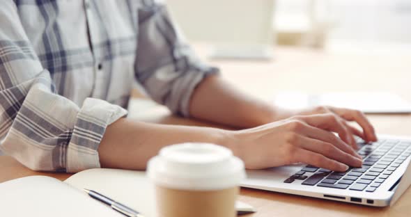 Businesswoman drinking coffee while working on laptop