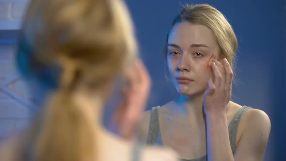 Terrified Young Woman Covering Face Wound With Concealer Front of Home Mirror