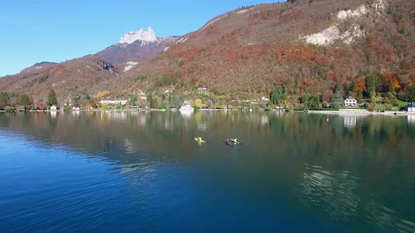 Three kayakers paddle in a scenic mountain lake.