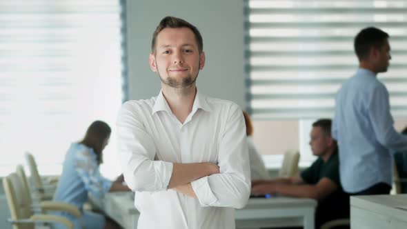 Successful Man in the Office in the Background Employees at Work Looking at the Camera