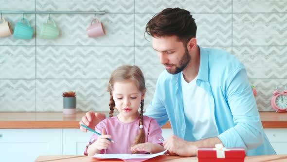 Young dad with little girl doing homework. Father teaching little daughter to write
