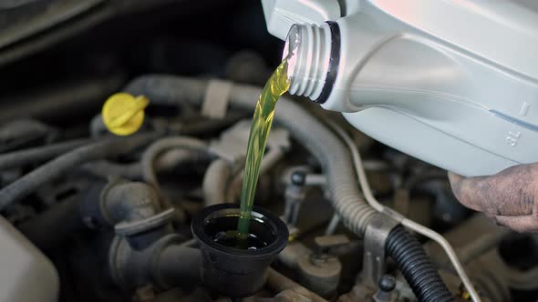 Pouring Fresh New Oil Into Car Engine In Repair Shop