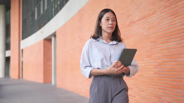 Young woman walking outdoors holding laptop computer