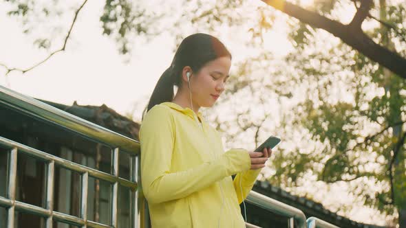 Smile of an athletic woman using smartphone while resting after workout running.