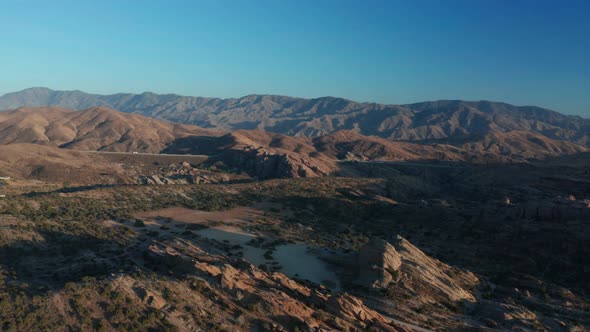 Desert landscape - Aerial footage of mountains and dry land with blue cloudy sky in the background.