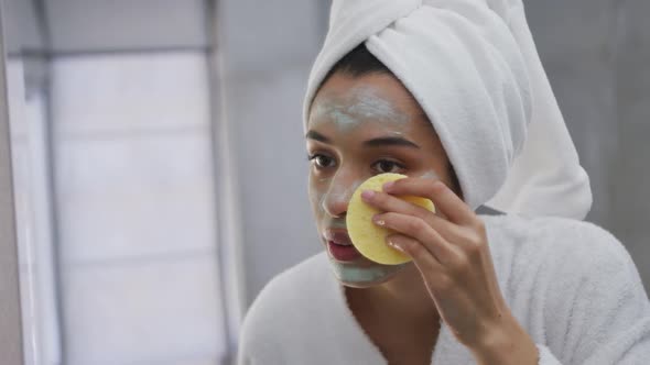 Mixed race woman removing face mask in bathroom