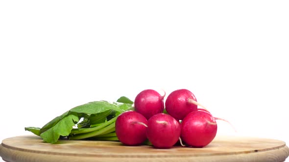 Bunch of Radishes Are Spinning on a Wooden Board. White Background