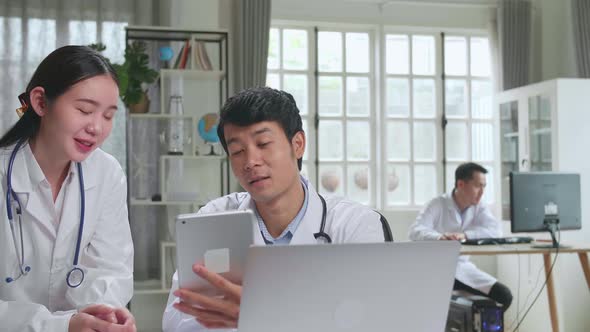 Two Asian Professional Physicians Talking, Consulting And Working On Tablet