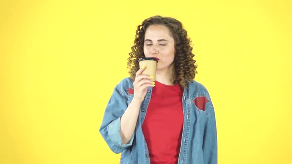 Girl Drinks Aromatic Coffee on Yellow Background at Studio, Slow Motion