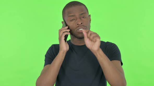 Young African Man Talking on Phone on Green Background