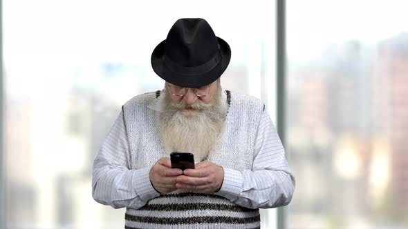 Senior Man Using Mobile Phone on Blurred Background.