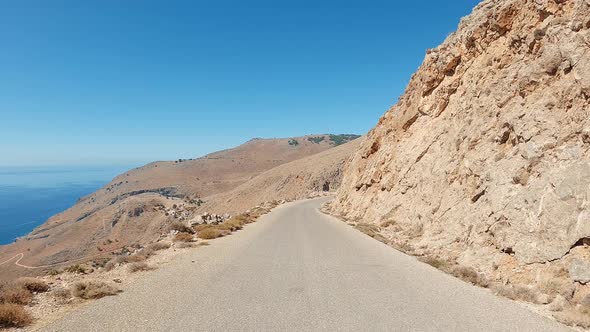 Car ride point of view on the asphalt coastal narrow Zig-zag curve road on a dramatic landscape.