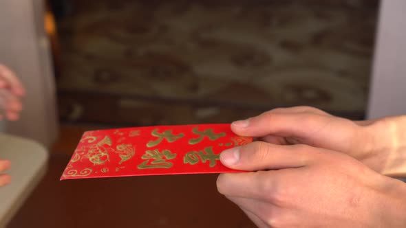 A Man Gives a Child a Red Hongbao Envelope with Money