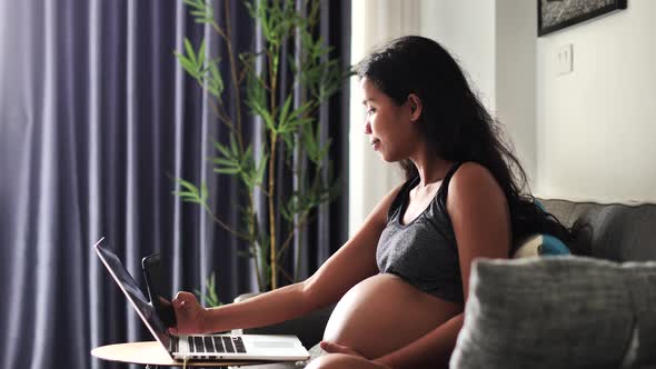 Young Pregnant Woman Sitting on the Sofa in the Living Room Taking Selfie Photos