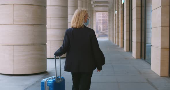 Follow Shot of Stylish Female Manager in Safety Mask with Suitcase Walking Outside Office Building