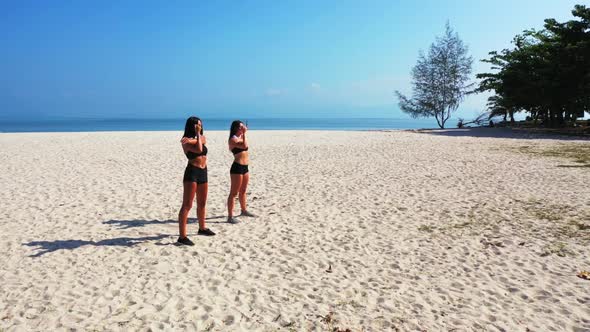 Girls posing on tropical tourist beach voyage by blue green water with white sand background of Thai