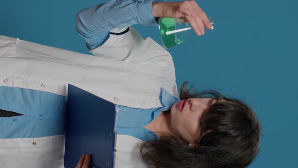 Vertical Video Female Scientist Analyzing Liquid in Beaker and Chemistry Files alt