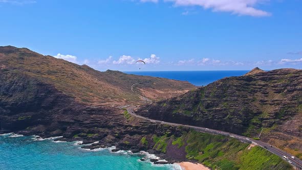 Aerial view of paraglider sailing above the rocky coastline of Makapuu