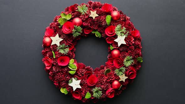 Top View of a Large Christmas Wreath Made with Red Ornaments Placed on Black Plain Background