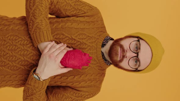 Vertical Shot of a Serious Caucasian Bearded Millennial Guy in Eyewear and a Beanie Holding Red