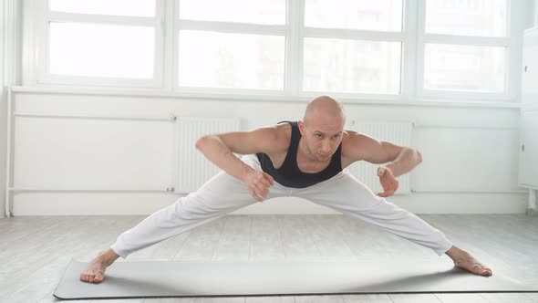 Young Flexible Male Training Doing Complex Yoga Exercises in Studio