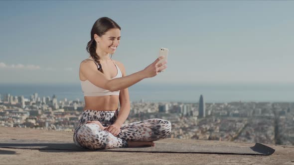 Sportsoman Taking Selfie on Smartphone at City. Yoga Woman Sitting in Lotus Pose