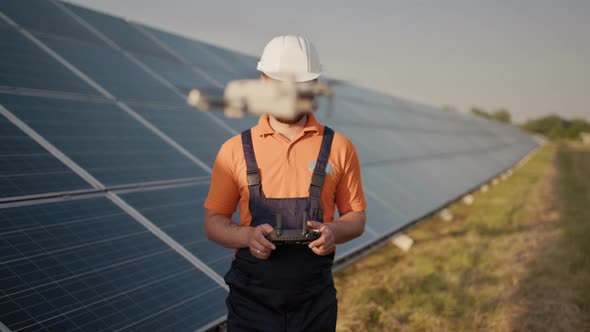 Industrial Expert Wearing Helmet and Controlling Drone in Photovoltaic Solar