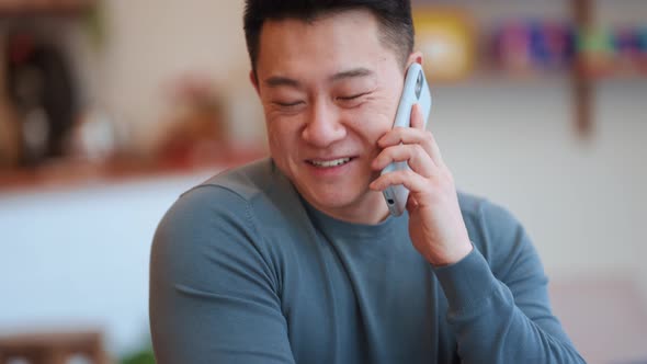 Positive Asian young man talking by phone