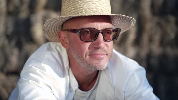 Headshot Portrait of Satisfied Caucasian Man in Straw Hat and Sunglasses Looking Away Smiling