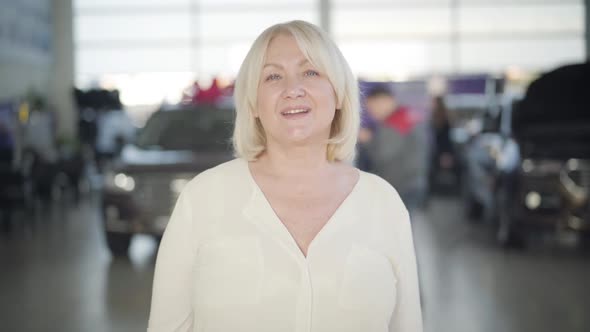 Portrait of Beautiful Senior Blond Caucasian Woman with Grey Eyes Looking at Camera and Smiling