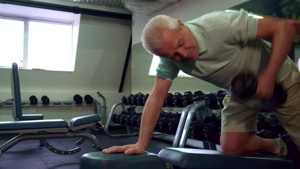 Senior Man Pulls Dumbell Up on the Bench