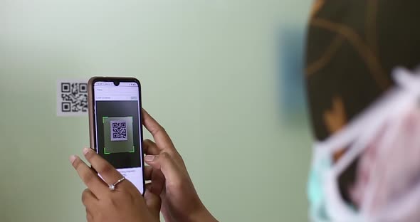 Female employee scans barcode to register attendance using smartphone and app