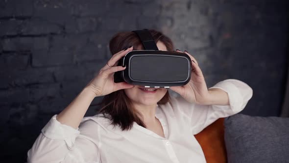 Attractive Woman in Virtual Reality Glasses Sitting on Sofa