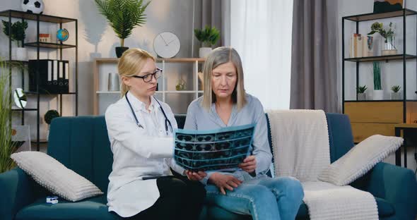 Doctor Sitting on the Couch Together with Female Patient and they Both Looking at X-ray Scan